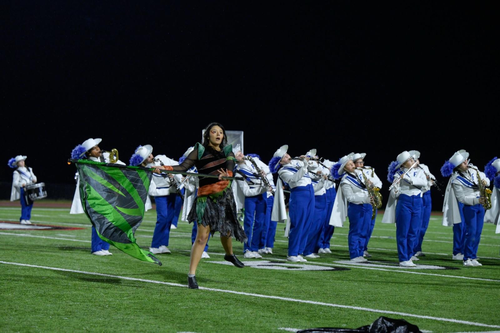 Color guard member leaping with a flag in front of the band